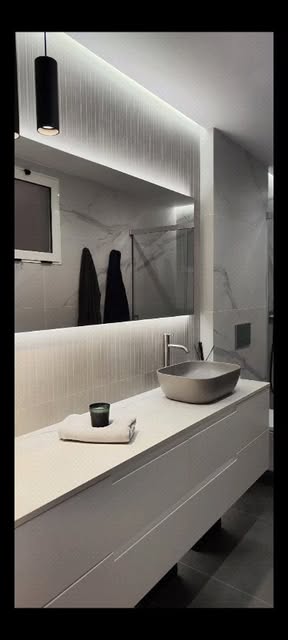 Baño con espejo retroiluminado y mármol