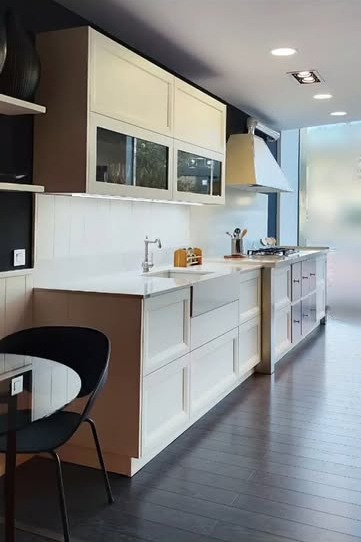 Foto real de la cocina terminada: muebles marfil, encimera blanca y suelo de madera oscura